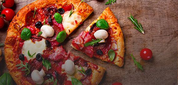 Sliced pizza with mozzarella, basil and pepperoni on a wooden board